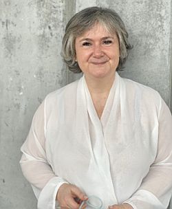 Das Foto zeigt einen Halbkörper-Ausschnitt von Gabriele Horcher in einer weißen Bluse, vor einer Betonwand stehend. Kommunikationswissenschaftlerin Gabriele Horcher ist Expertin für Business Development und Vertrieb.